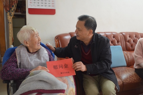 2市僑聯(lián)一級(jí)調(diào)研員黃志堅(jiān)（右）向印尼歸僑郭惠英送上慰問金_副本.jpg